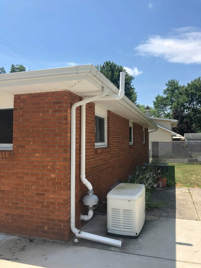 A photo of a radon reduction fan mounted on the exterior wall of a house, designed to expel radon gas from the basement.